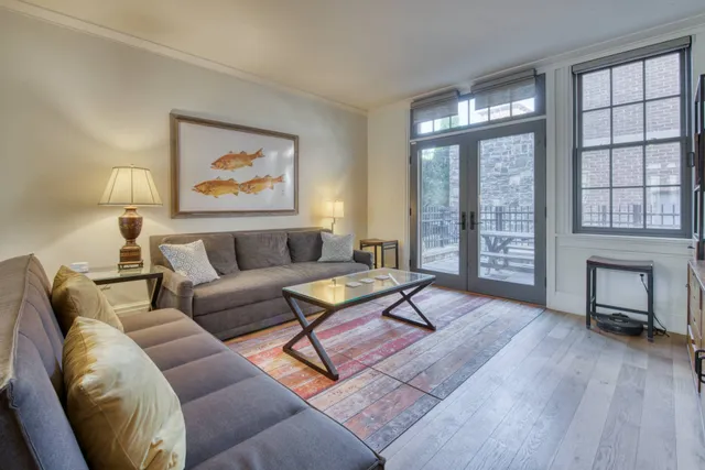 a living room with furniture a floor to ceiling window and wooden floor