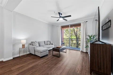 a living room with furniture large window and wooden floor