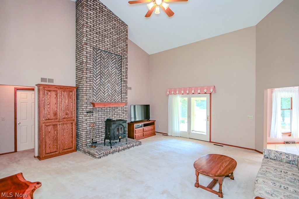 6475 Taylor Road Painesville, OH 44077 - Photo 5 of 23 Vaulted ceiling living area featuring a prominent brick fireplace with a herringbone pattern inlay, wood mantel, and wood-burning stove