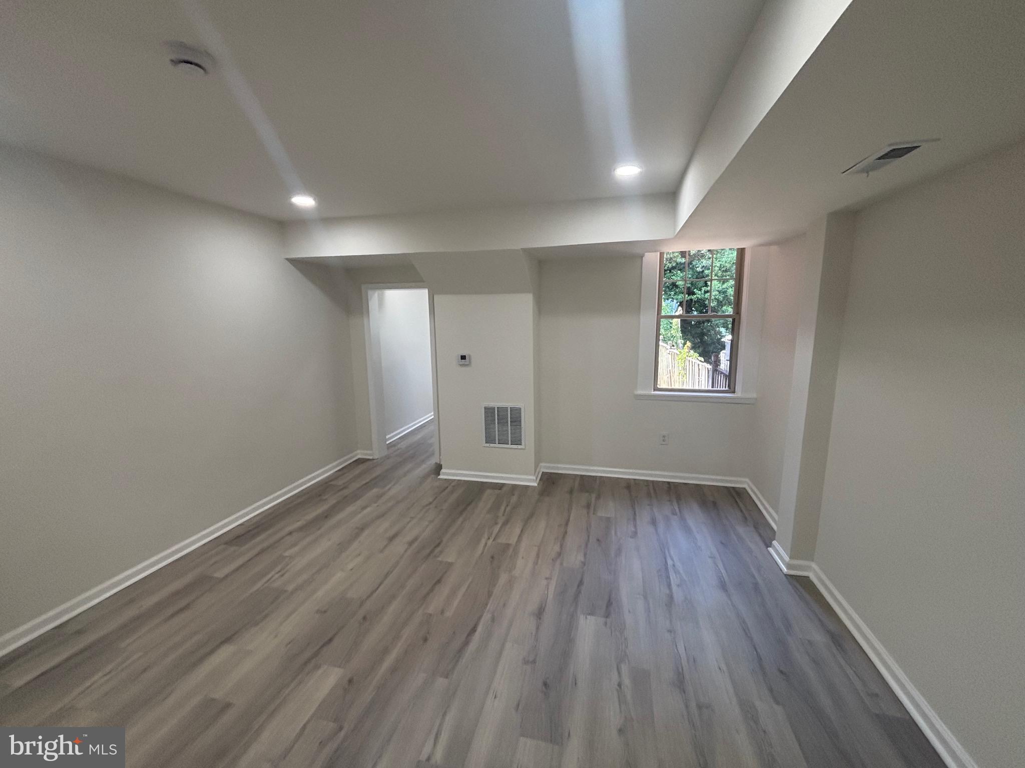 6769 Woodley Road Baltimore, MD 21222 - Photo 11 of 27 an empty room with wooden floor and window