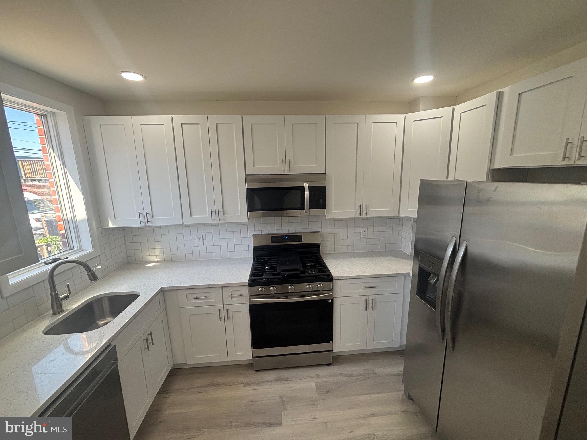 6769 Woodley Road Baltimore, MD 21222 - Photo 4 of 27 a kitchen with white cabinets and stainless steel appliances