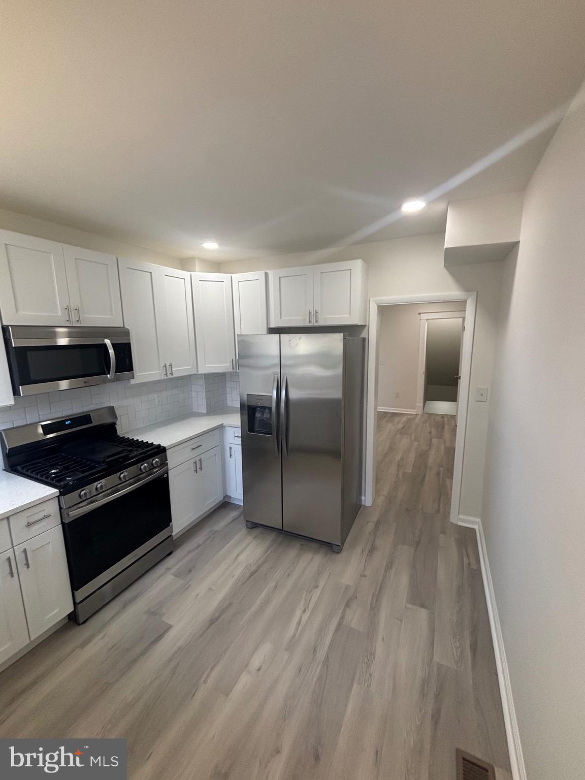 6769 Woodley Road Baltimore, MD 21222 - Photo 6 of 27 a kitchen with wooden floors appliances and cabinets