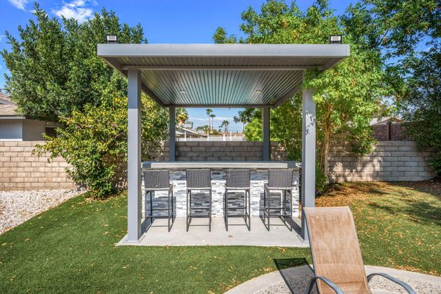 a view of a chair and table in backyard of the house