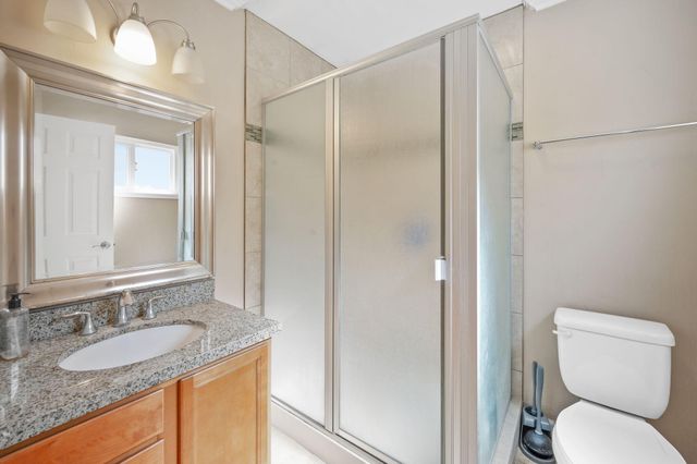 a bathroom with a granite countertop sink toilet and shower