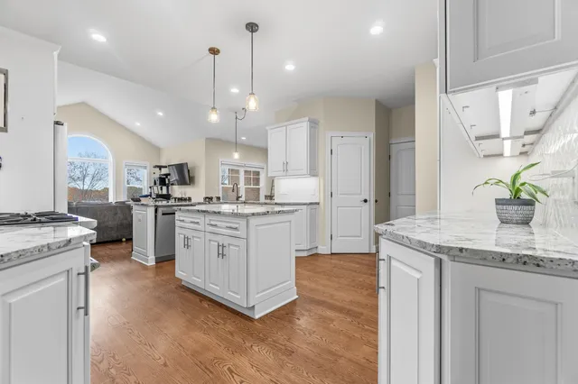 a kitchen with a white center island a sink stainless steel appliances and cabinets