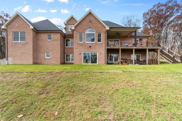 a view of a big house with a big yard and large trees