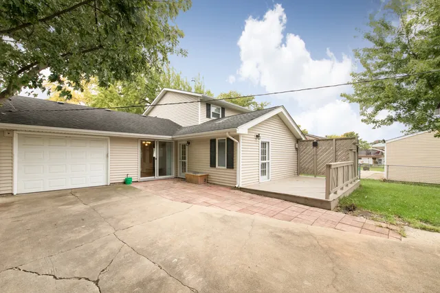 a view of house with backyard and trees in the background