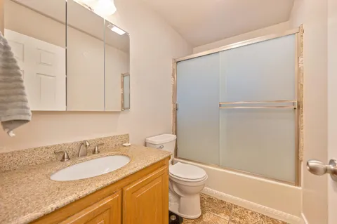 a bathroom with a granite countertop sink toilet and shower