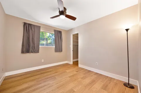 a view of an empty room with window and hardwood floor