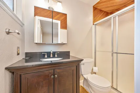 a bathroom with a granite countertop sink toilet and mirror