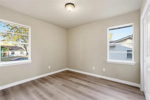 a view of an empty room with wooden floor and a window