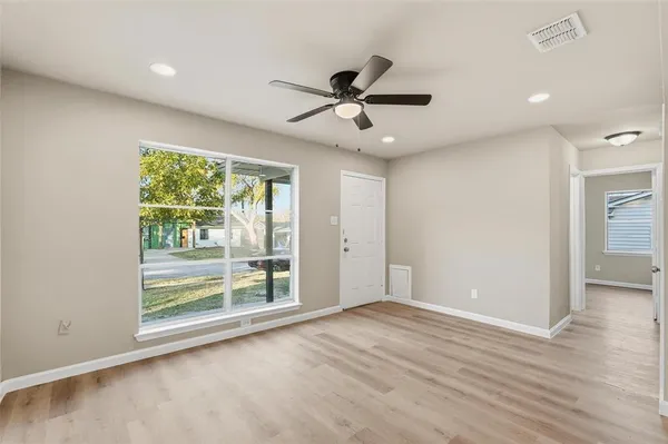 a view of an empty room with wooden floor and a window