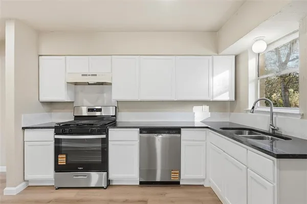 a kitchen with granite countertop a sink and a stove top oven