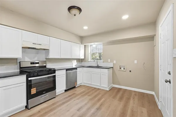 a kitchen with granite countertop white cabinets and stainless steel appliances