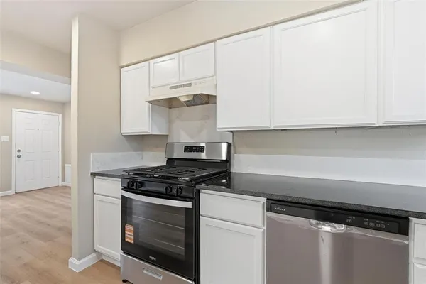a kitchen with white cabinets and appliances