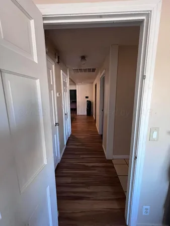 a view of a hallway with wooden floor and stairs