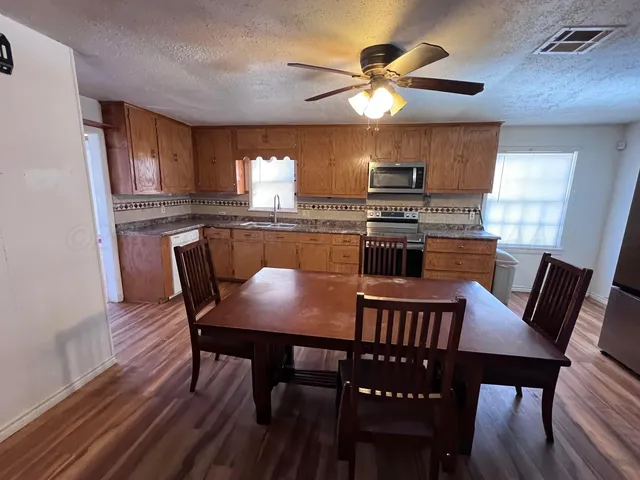 a kitchen with stainless steel appliances granite countertop a dining table and chairs
