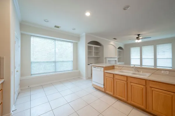 an empty room with a chandelier fan and windows