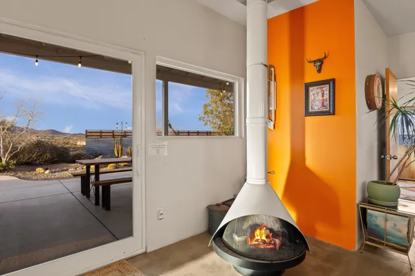 a living room with furniture a rug kitchen view and a large window