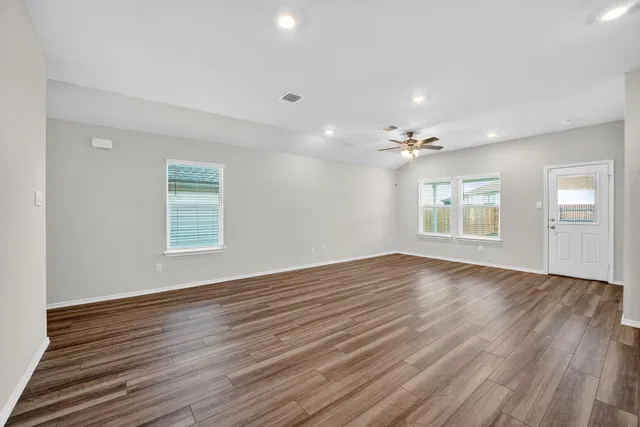 a view of an empty room with a window and wooden floor