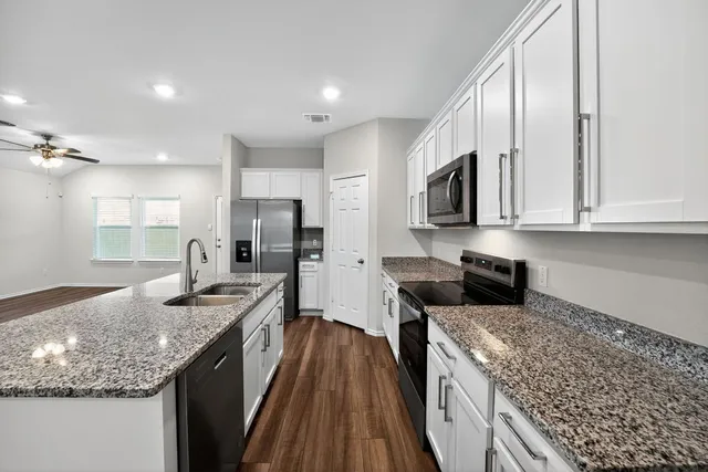 an empty room with chandelier fan and windows