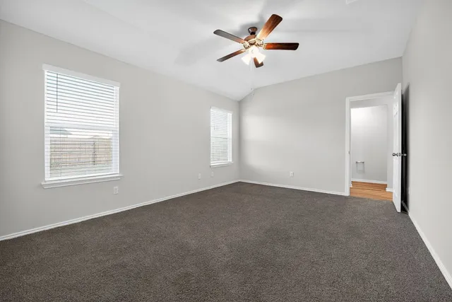an empty room with windows and fan