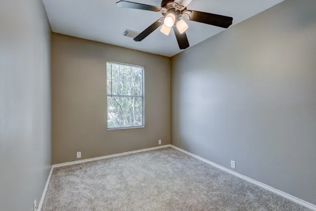 an empty room with a window and a fan