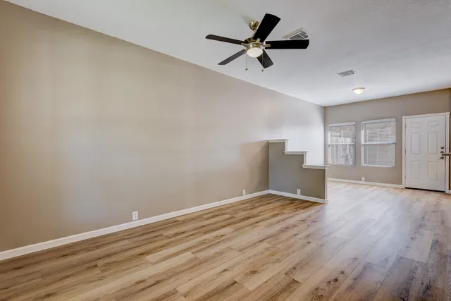 a view of empty room with wooden floor and ceiling fan