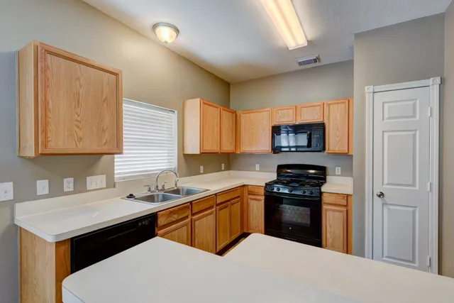 a kitchen with stainless steel appliances a sink a stove a refrigerator a sink a counter space and cabinets