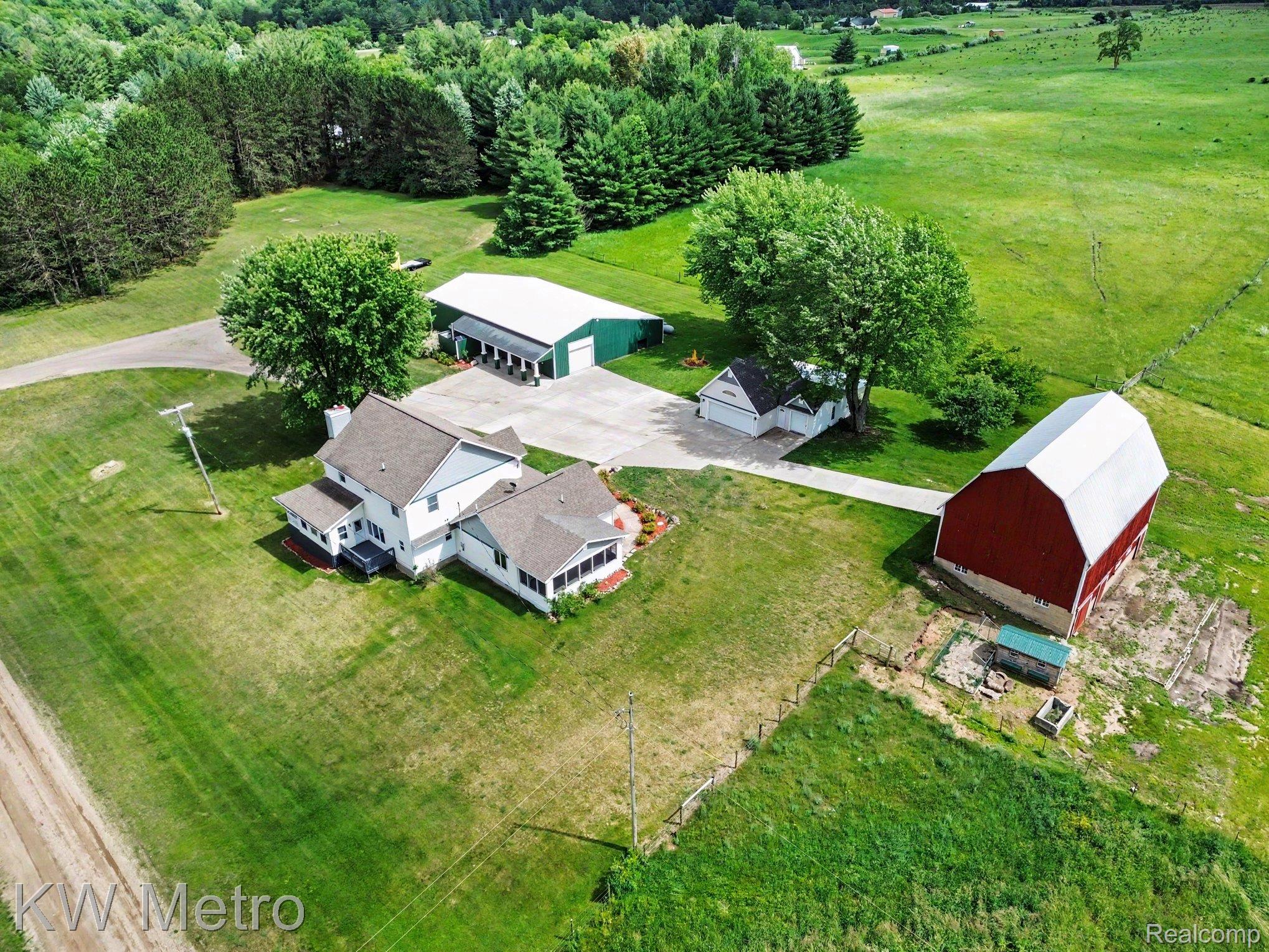 2682 East Haskell Lake Road Harrison, MI 48625 - Photo 3 of 61 Expansive property featuring a white residence with a screened porch, a red barn, a large green outbuilding, a detached white garage, and substantial green space with mature trees