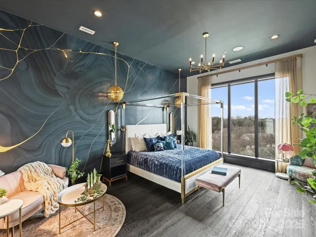 a spacious bedroom with a bed a chandelier and potted plant