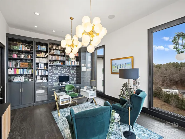 a living room with couches chandelier and a large window with garden view