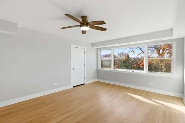 an empty room with wooden floor fan and windows