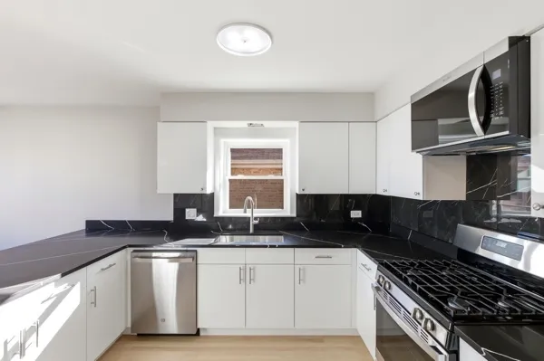 a kitchen with granite countertop a sink stove and microwave