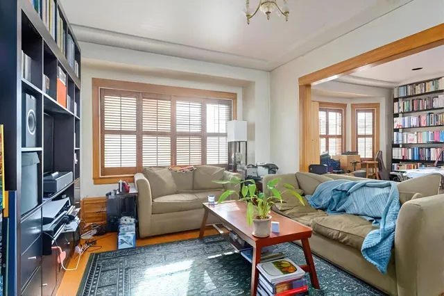 a living room with furniture a bookshelf and a window