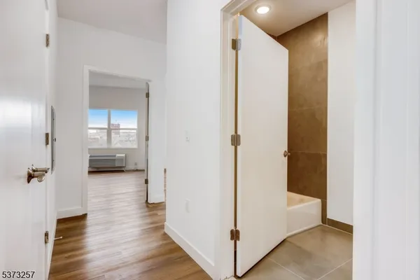 a view of a hallway with wooden floor and a bathroom