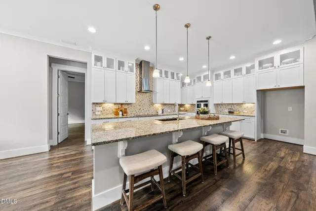a large kitchen with kitchen island a dining table chairs and a wooden floor
