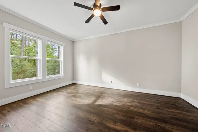 an empty room with wooden floor chandelier fan and windows