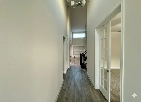 a view of a hallway with wooden floor and a bathroom