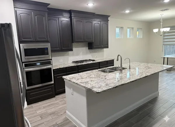 a kitchen with kitchen island granite countertop a sink stove and refrigerator