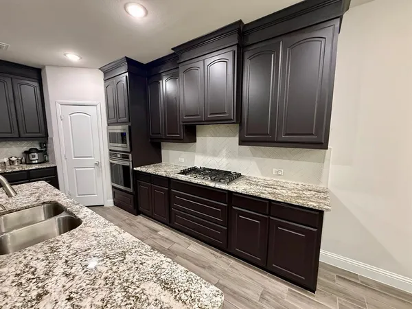 a kitchen with stainless steel appliances granite countertop wooden cabinets a refrigerator and a sink