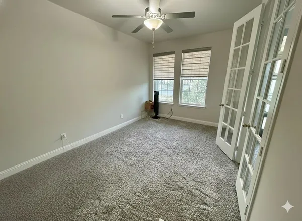 an empty room with windows and fan
