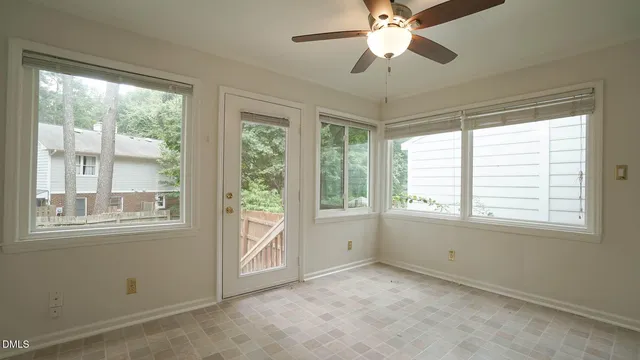 an empty room with chandelier fan and windows
