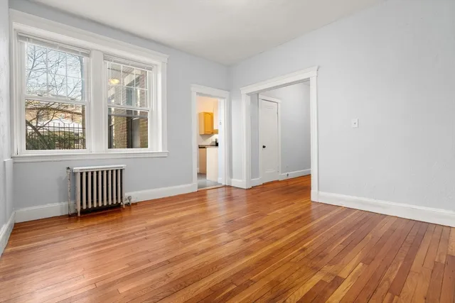 a view of an empty room with wooden floor and a window