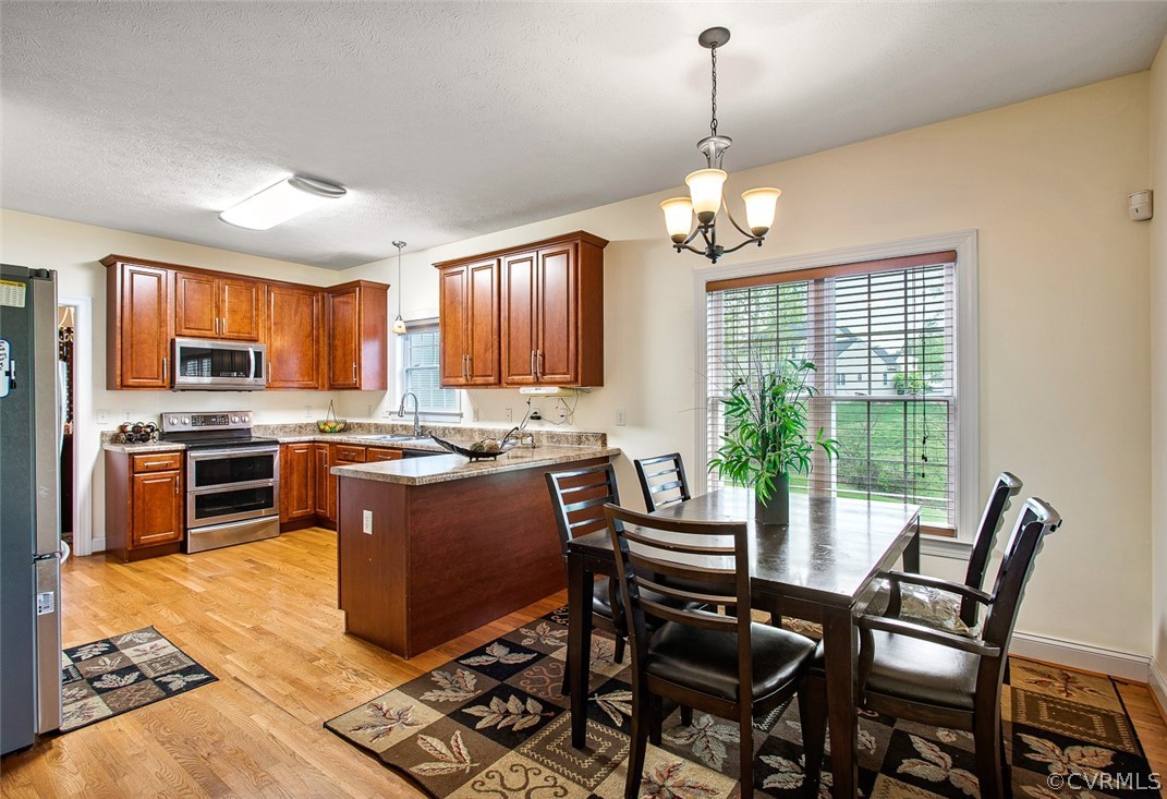 3001 Barnack Road Midlothian, VA 23112 - Photo 15 of 37 a kitchen with stainless steel appliances granite countertop a stove top oven a sink dishwasher a dining table and chairs with wooden floor