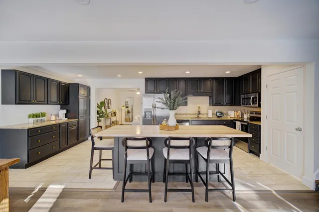 a kitchen with stainless steel appliances kitchen island granite countertop a dining table chairs sink and cabinets