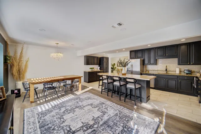 a living room with stainless steel appliances furniture a rug and a kitchen view