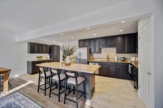 a kitchen with stainless steel appliances kitchen island granite countertop a stove a sink a refrigerator a dining table and chairs