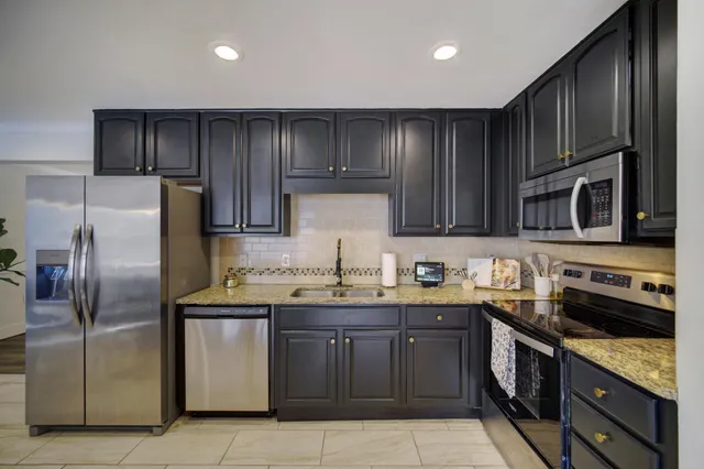 a kitchen with stainless steel appliances granite countertop a stove a sink dishwasher a refrigerator and a microwave
