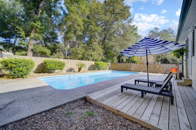 a view of a roof deck with table and chairs under an umbrella with wooden floor